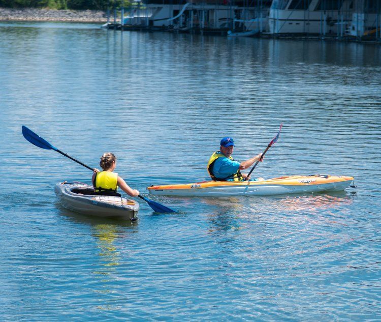 a man and a woman are paddling kayaks on a lake .