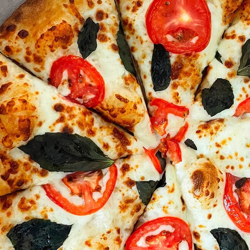 A close up of a pizza with tomatoes and basil on it.
