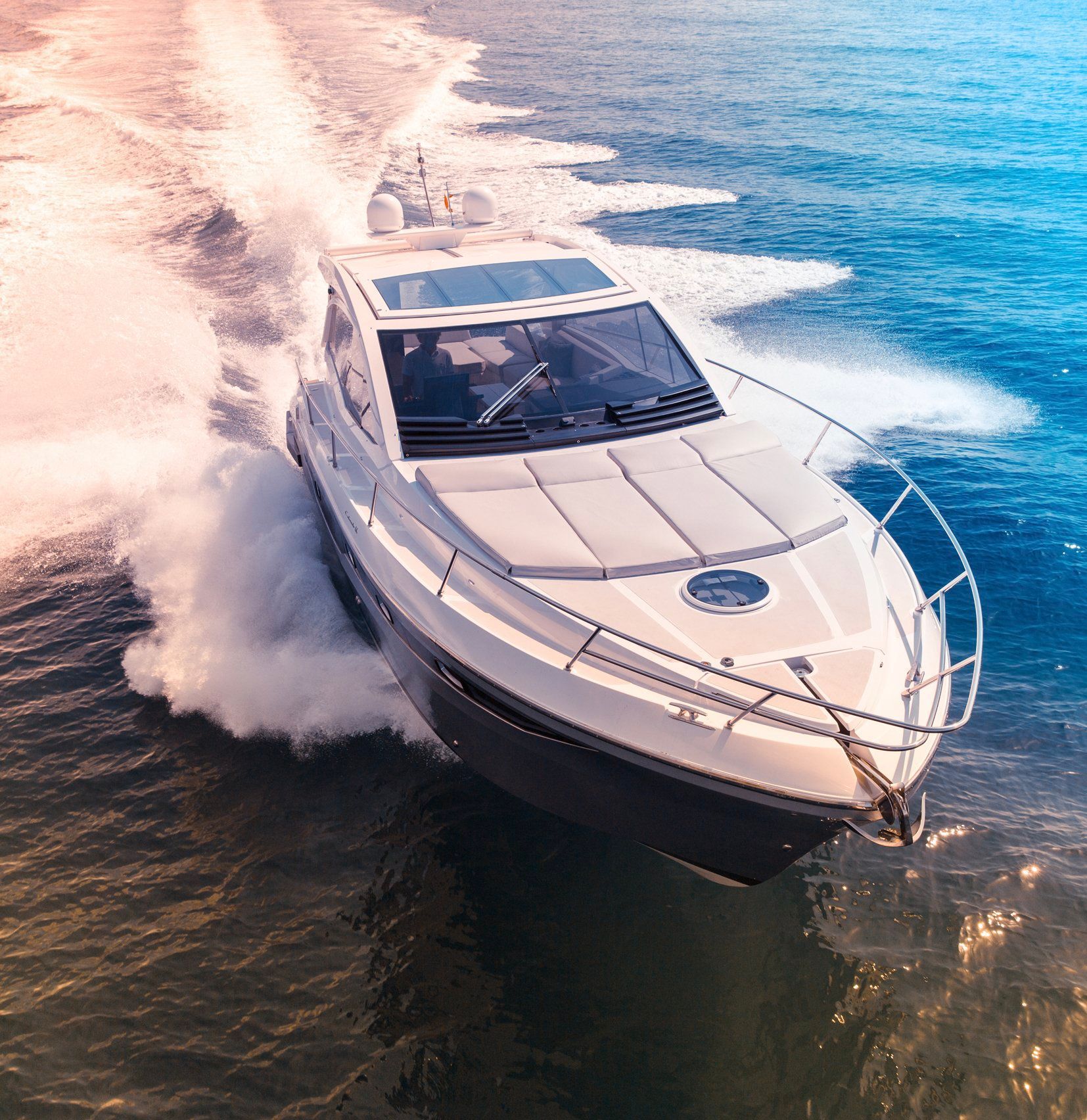 a white yacht is floating on top of a large body of water .
