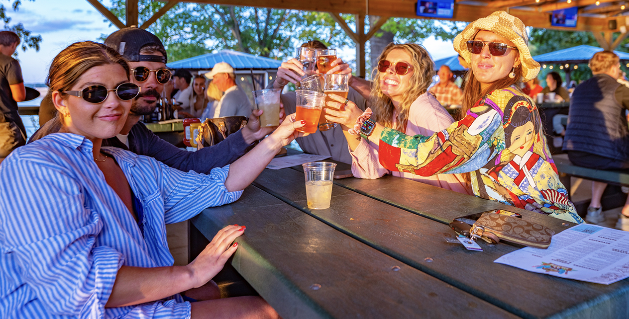 A woman is holding a tray of drinks on a deck.