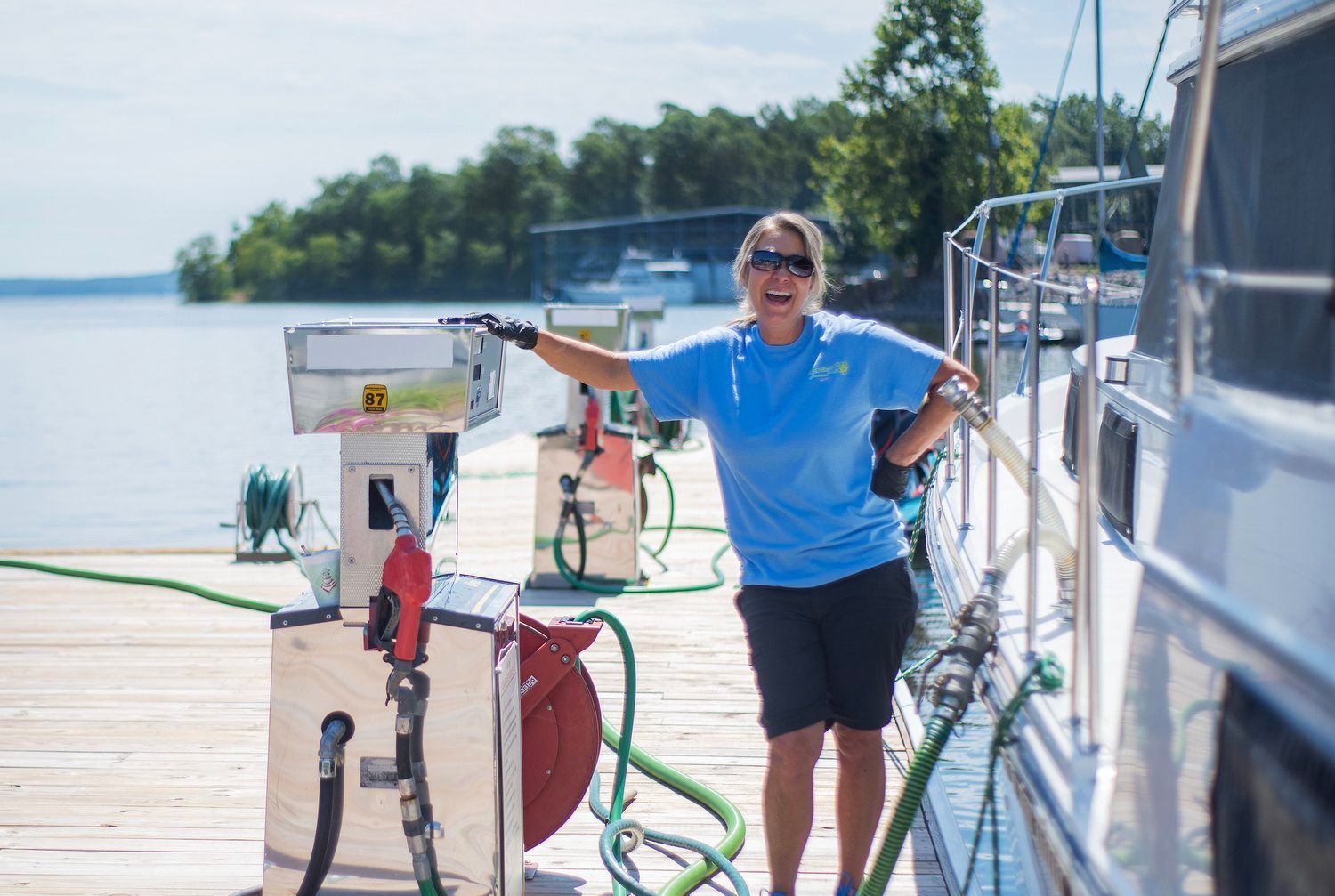 A woman is pumping gas into a boat on a dock.