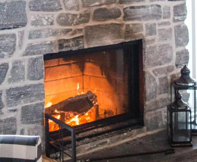 There is a fireplace in the middle of a stone wall.