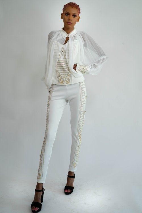 A woman is wearing a white top and white pants