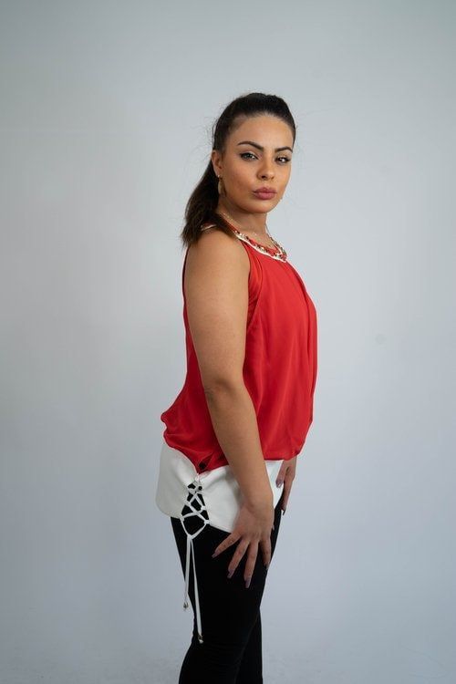 A woman is wearing a red tank top and black pants.