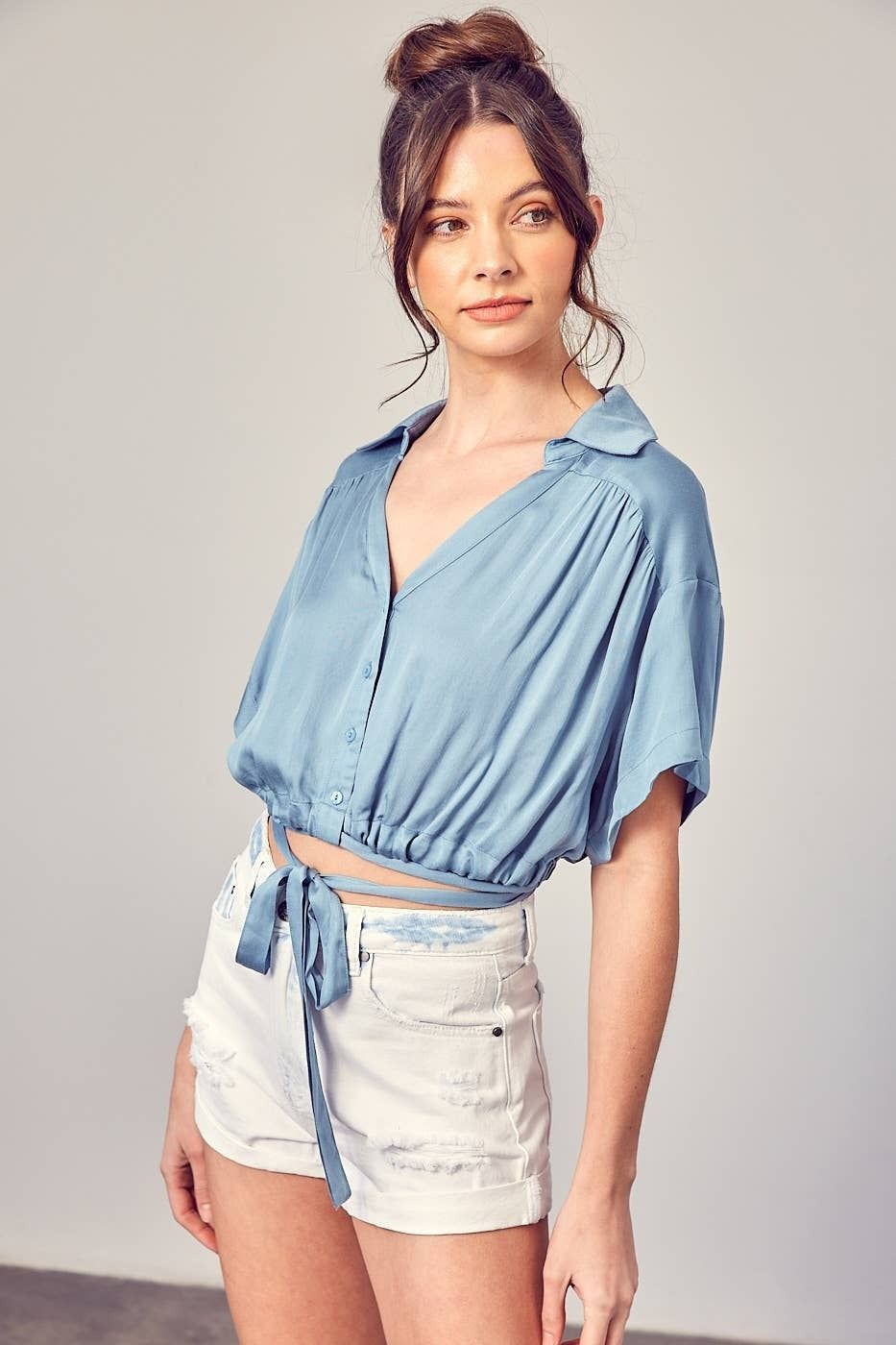 A woman is wearing a blue crop top and white shorts.