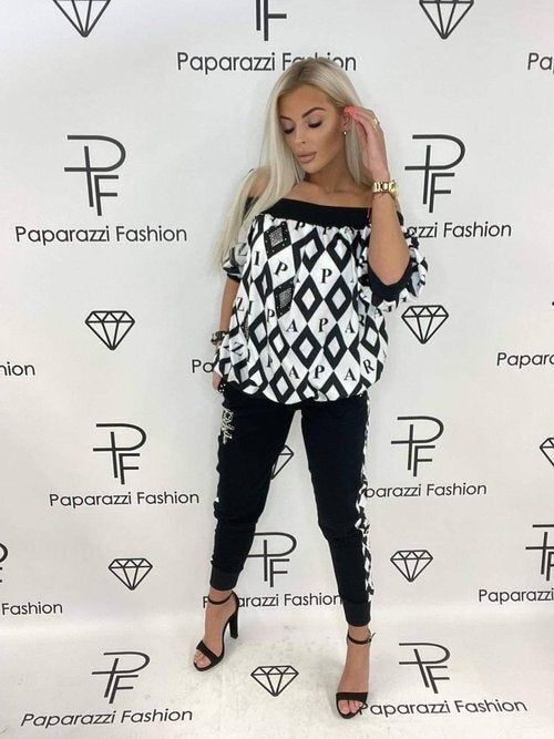 A woman is standing in front of a paparazzi fashion wall
