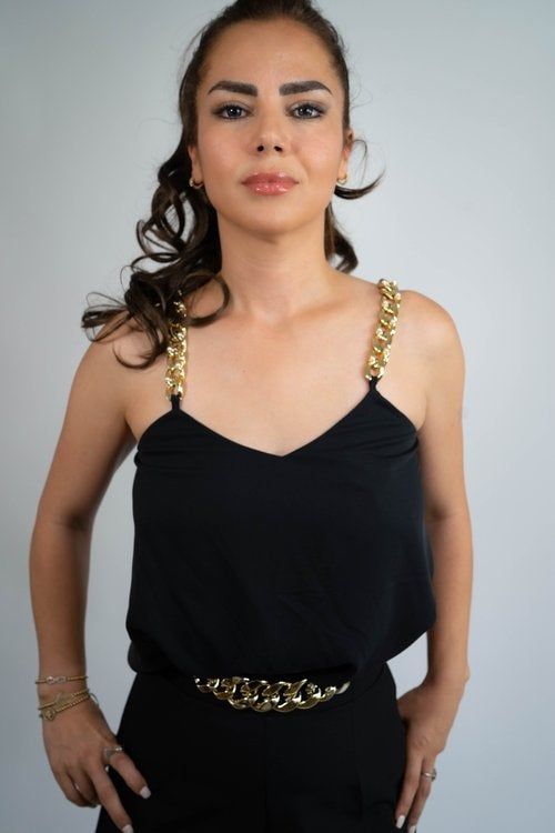 A woman wearing a black tank top with gold straps