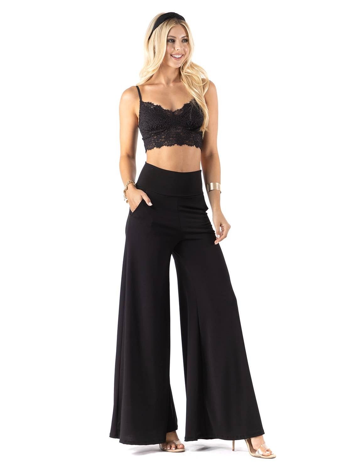 A woman is wearing a crop top and wide leg pants.