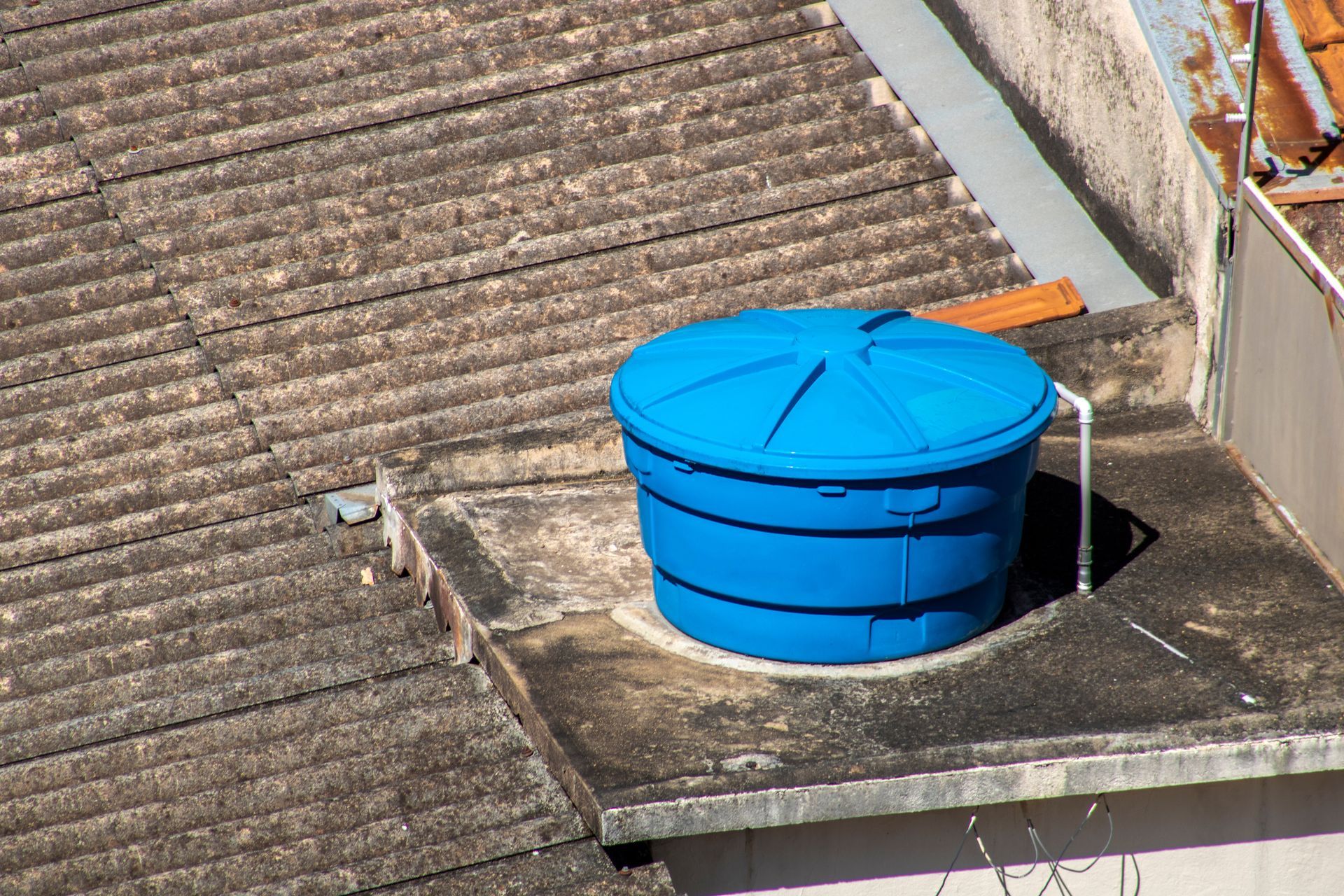 Un tanque de agua azul está en el techo de un edificio.