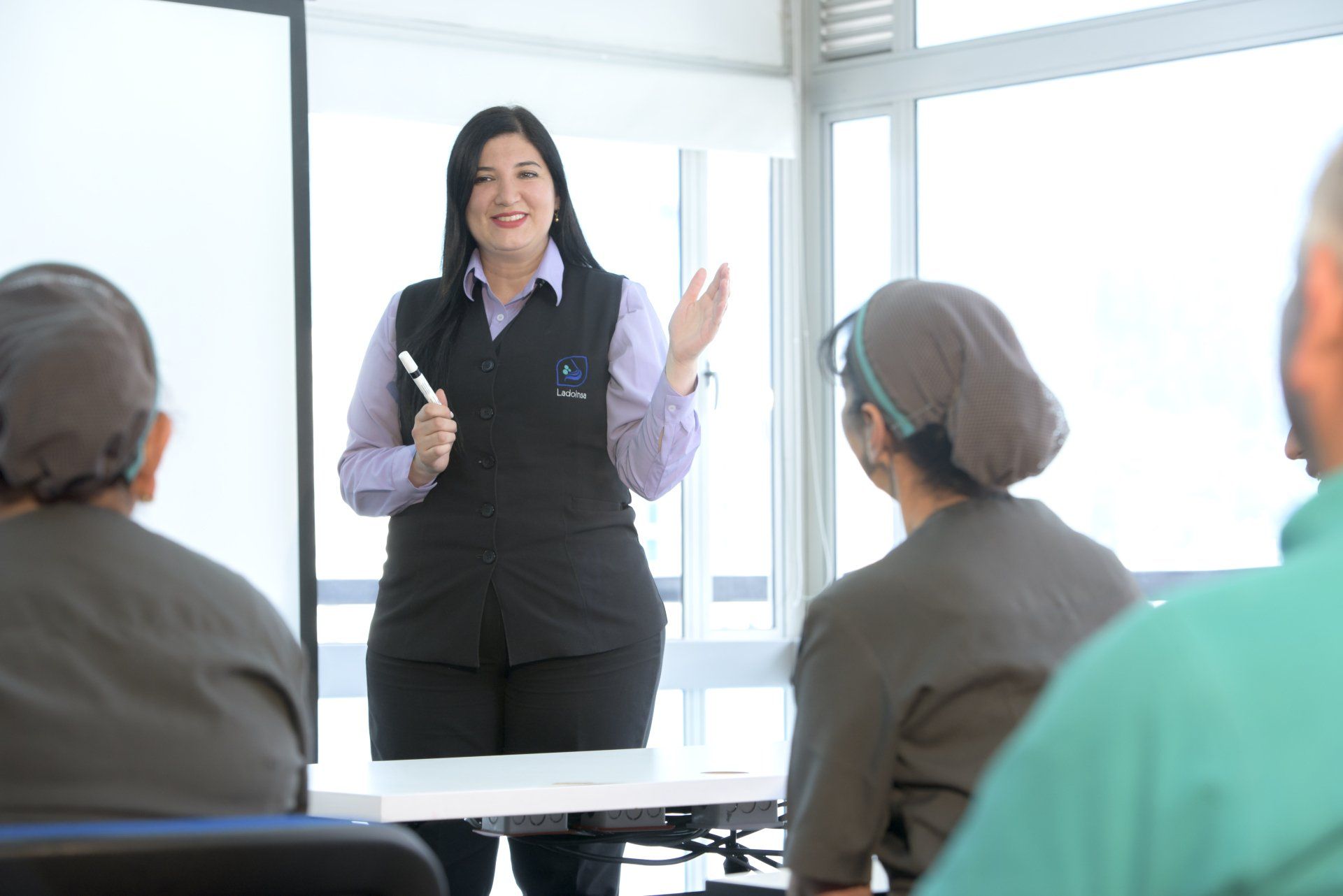Una mujer está dando una presentación a un grupo de personas sentadas en una mesa.