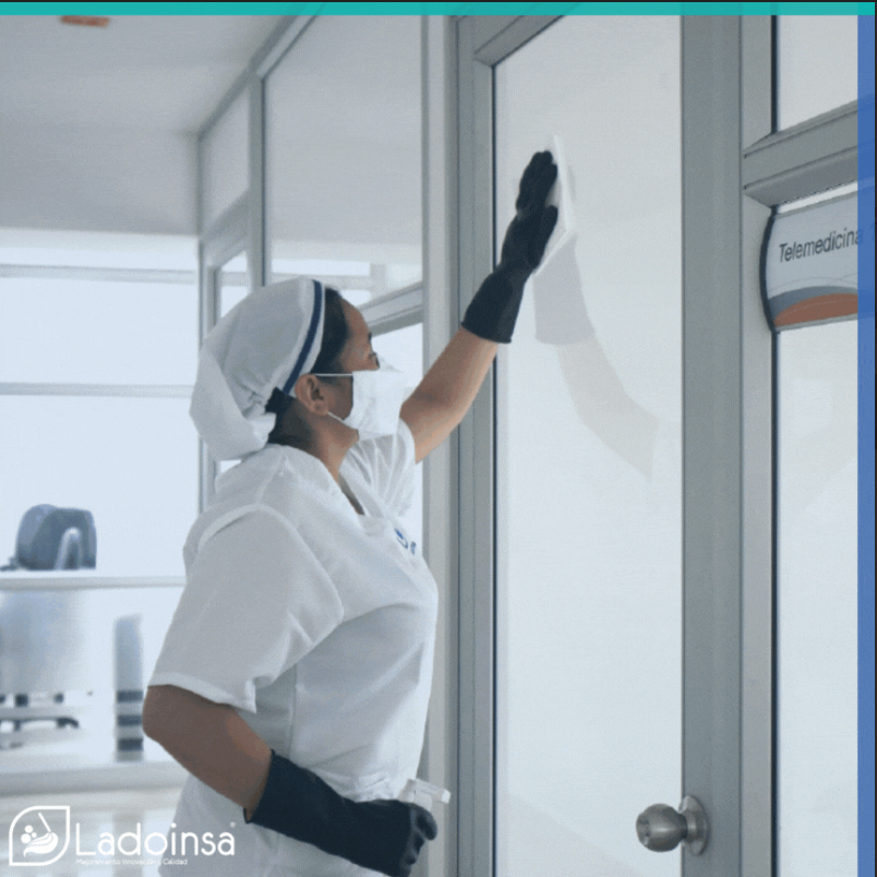 Una mujer con mascarilla y guantes está limpiando una puerta.