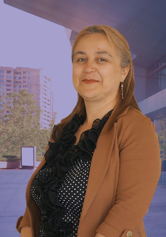 Una mujer con una chaqueta marrón y una camisa de lunares negros está parada frente a un edificio.