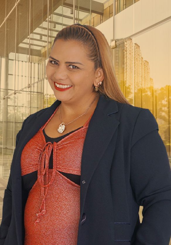 Una mujer con un vestido rojo y una chaqueta negra sonríe frente a un edificio.