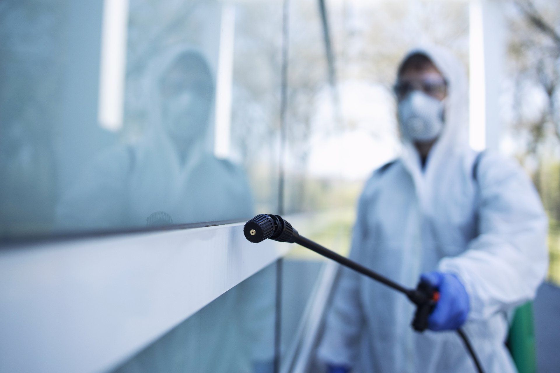 Un hombre con un traje de protección está rociando una ventana con un pulverizador.