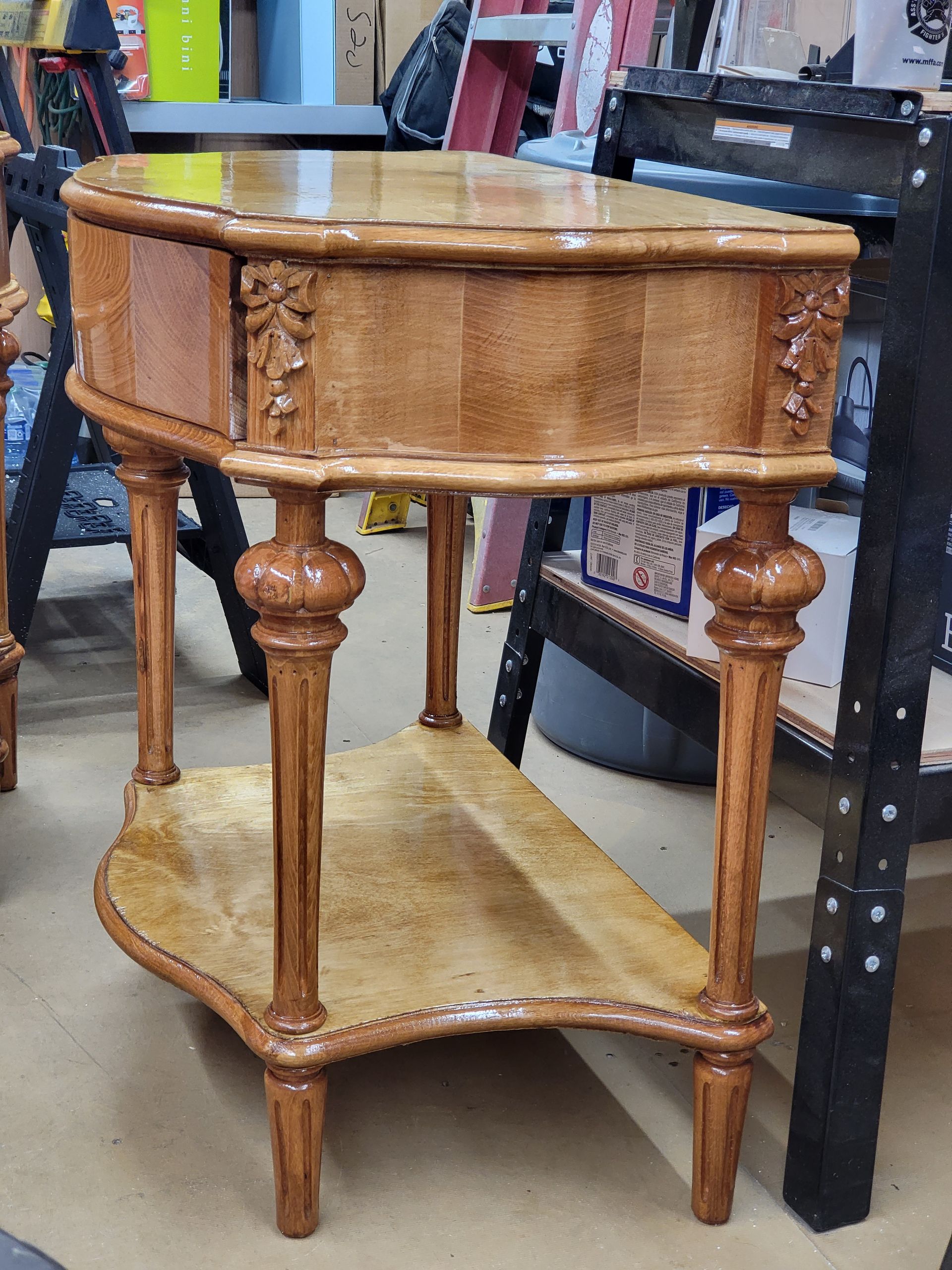 Wooden, oval-shaped side table with a drawer, intricate carvings, and a lower shelf.