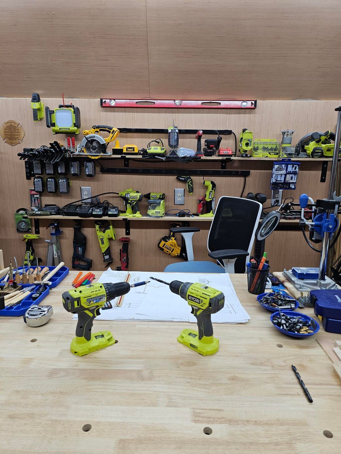 Two Ryobi drills on a workbench with a variety of tools in a workshop setting.