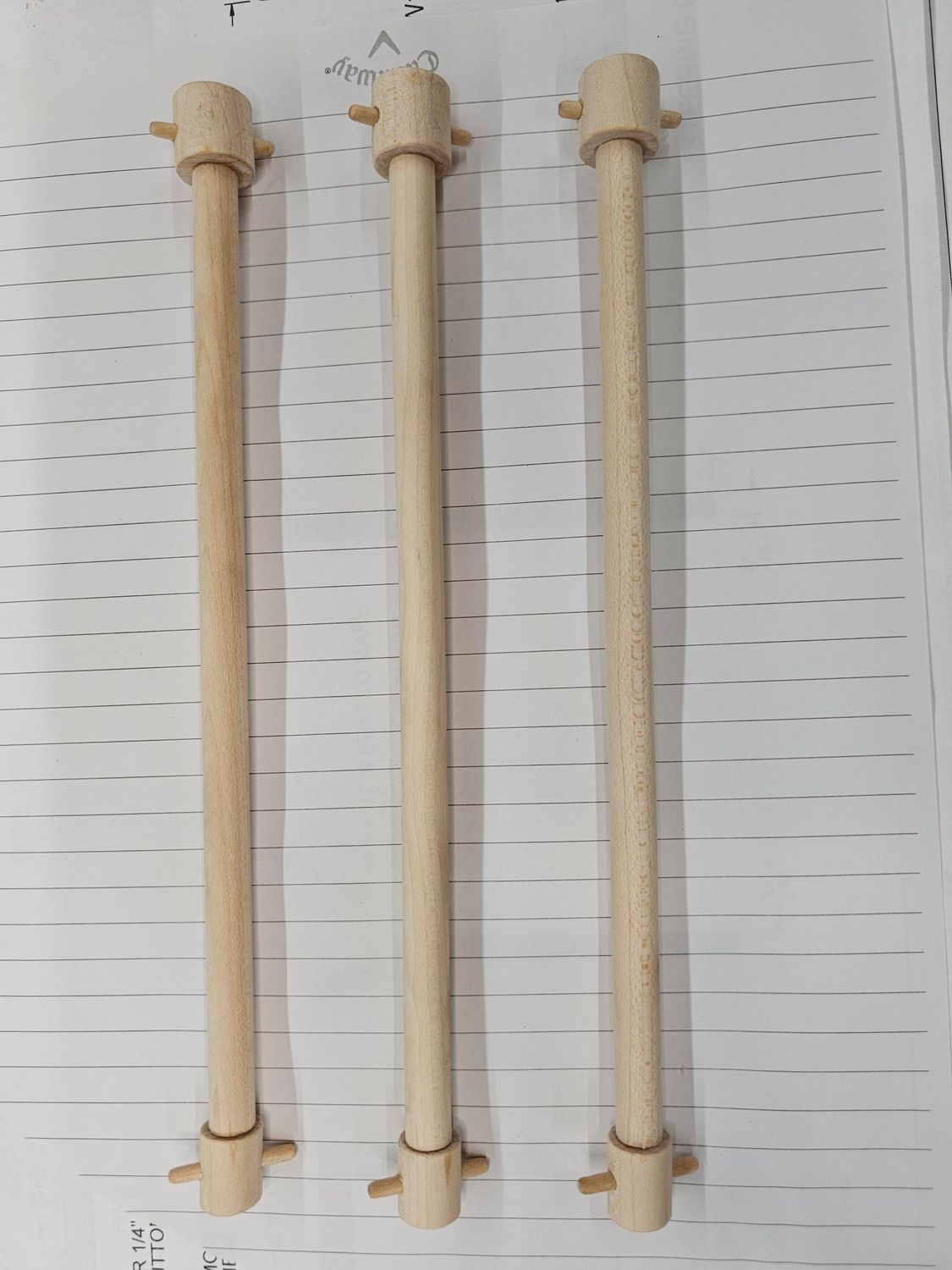 Three wooden dowels, each with a wider top and bottom, and small protrusions mid-length.