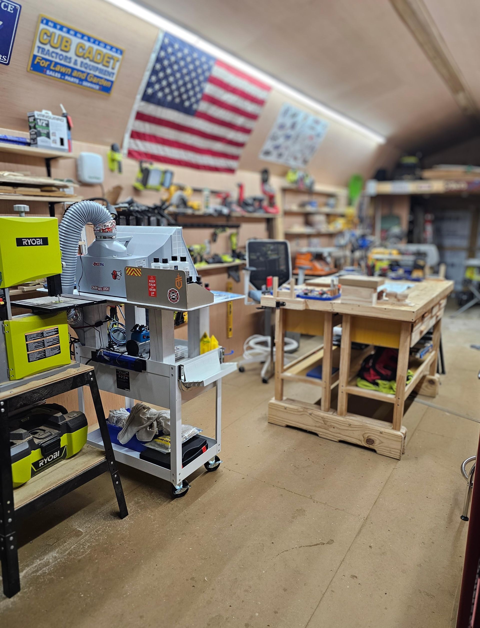 Woodworking shop interior with tools, a workbench, and American flags.