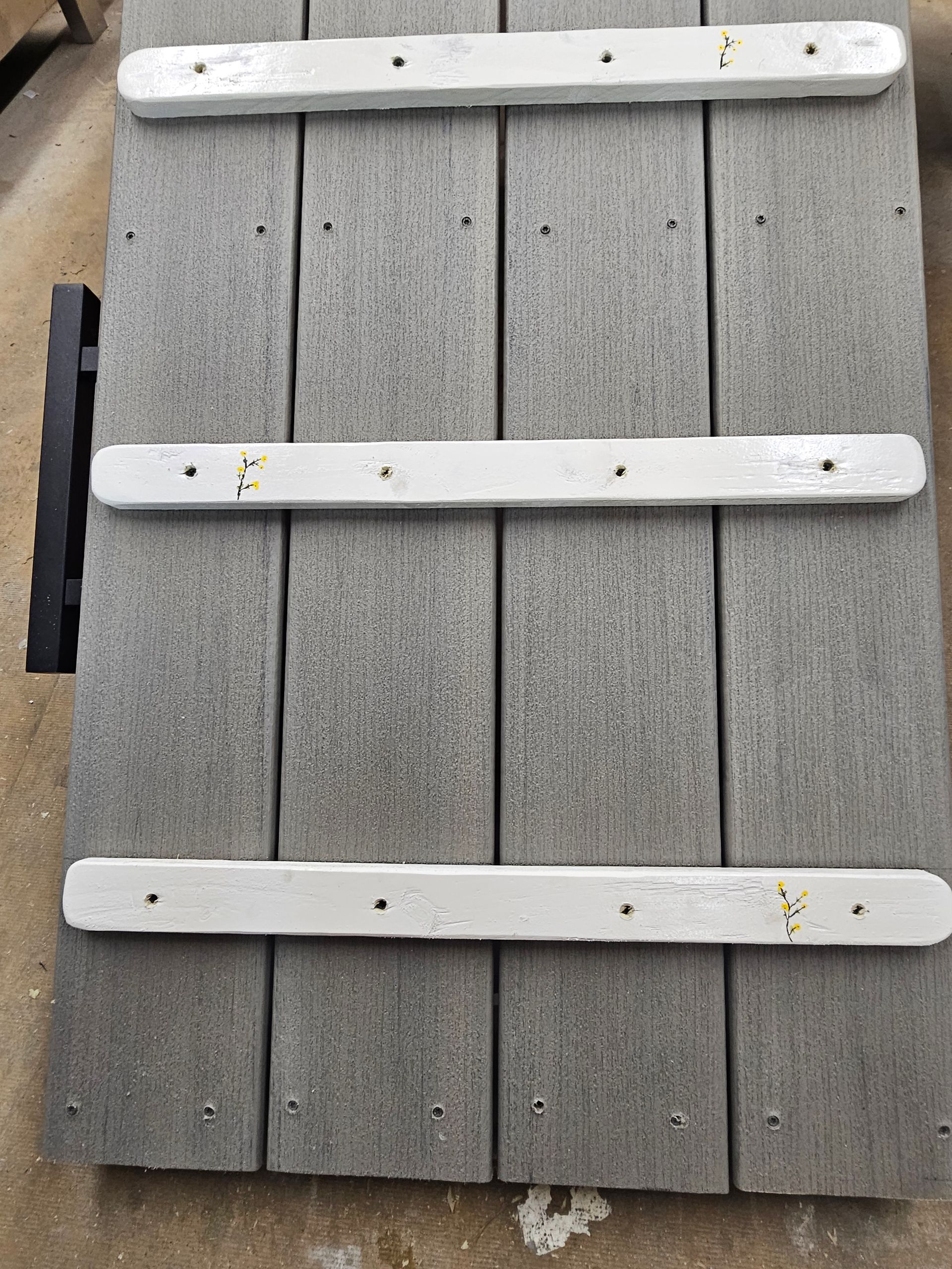 Gray and white composite panel. Three white battens are attached with screws.