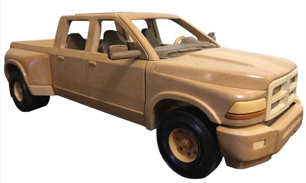Wooden model of a tan pickup truck with black tires and tinted windows.