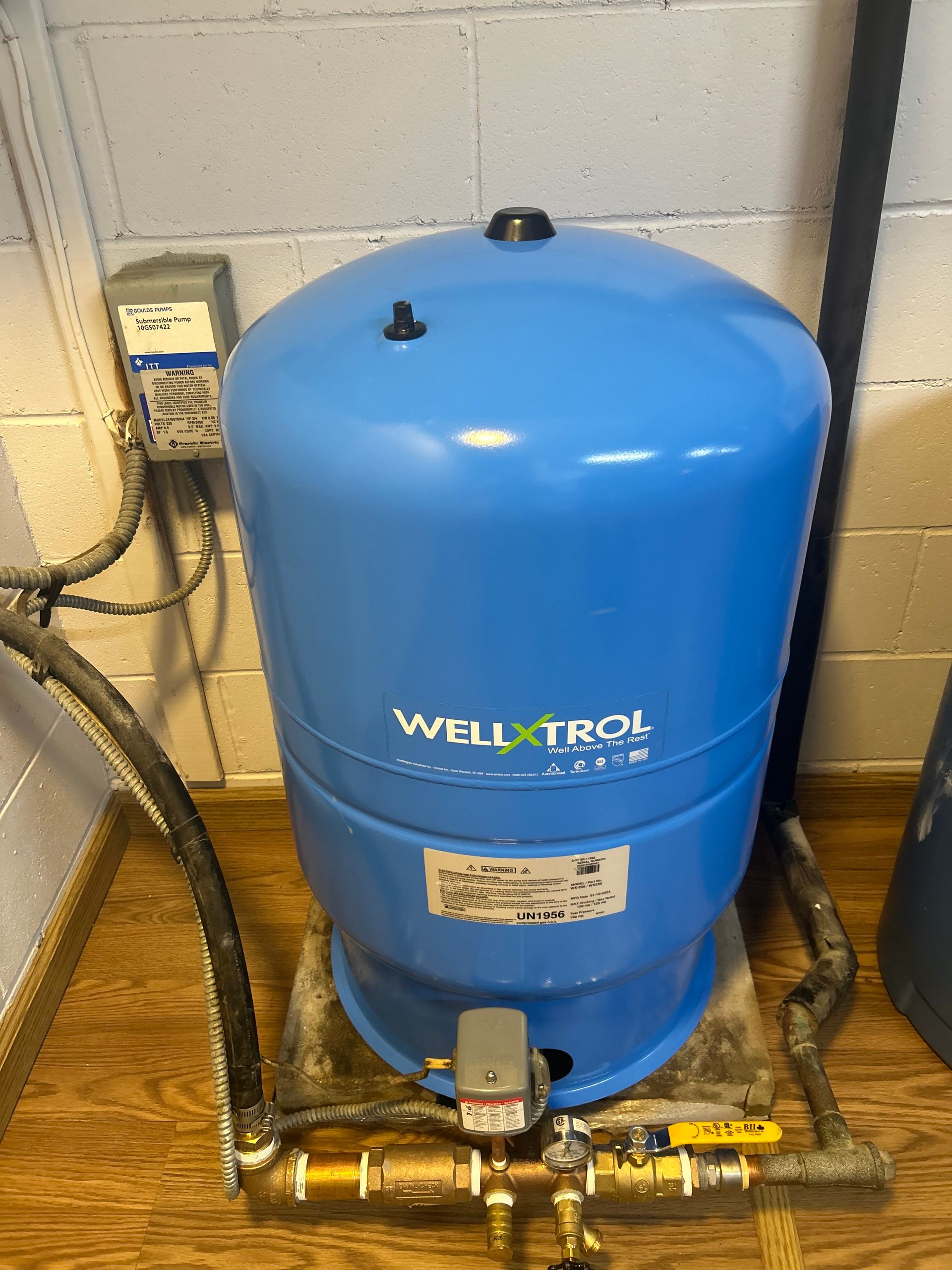 Blue Well-X-Trol water tank with plumbing in a utility room.