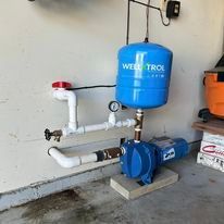 Blue well pump system installed against a white wall.