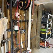 Wooden wall with hose reels, pipes, and tools.