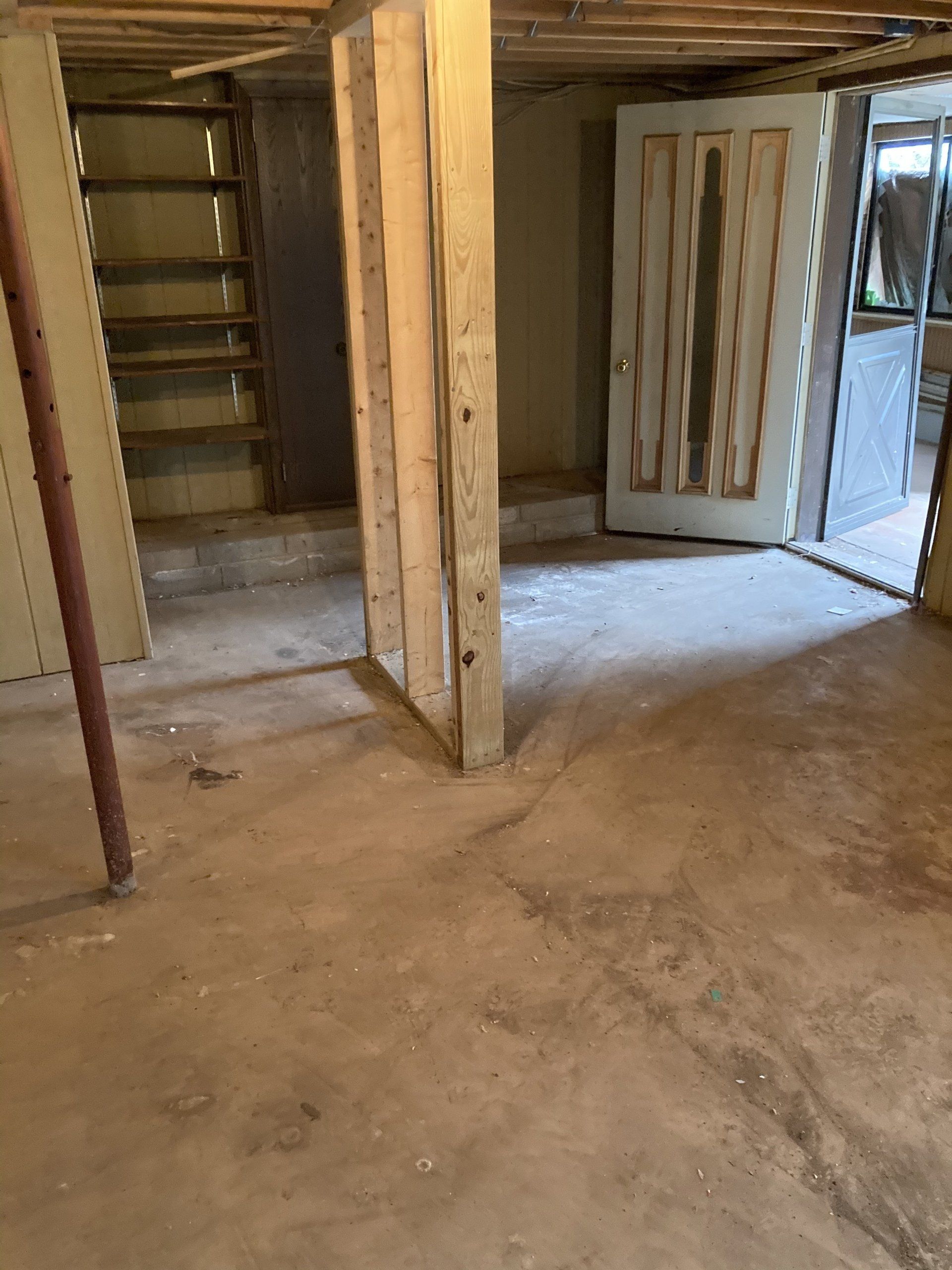 An empty basement with a door and stairs.