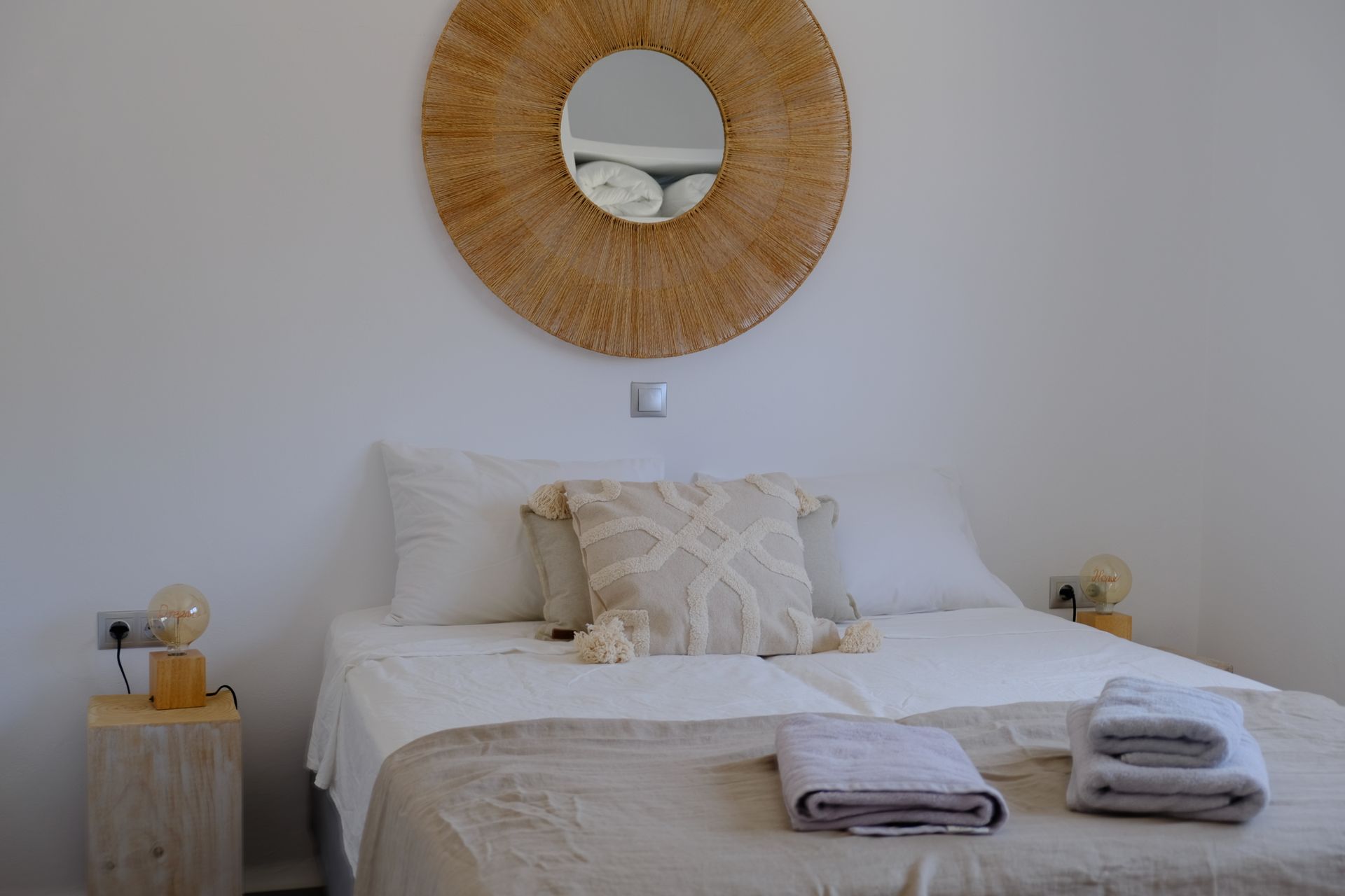 A bedroom with a bed and a mirror on the wall.