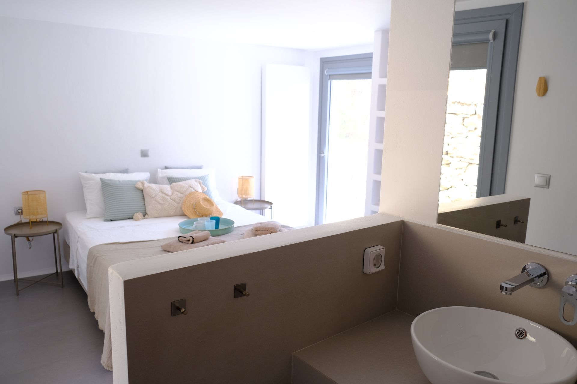 A bathroom with a sink and a bed in the background.