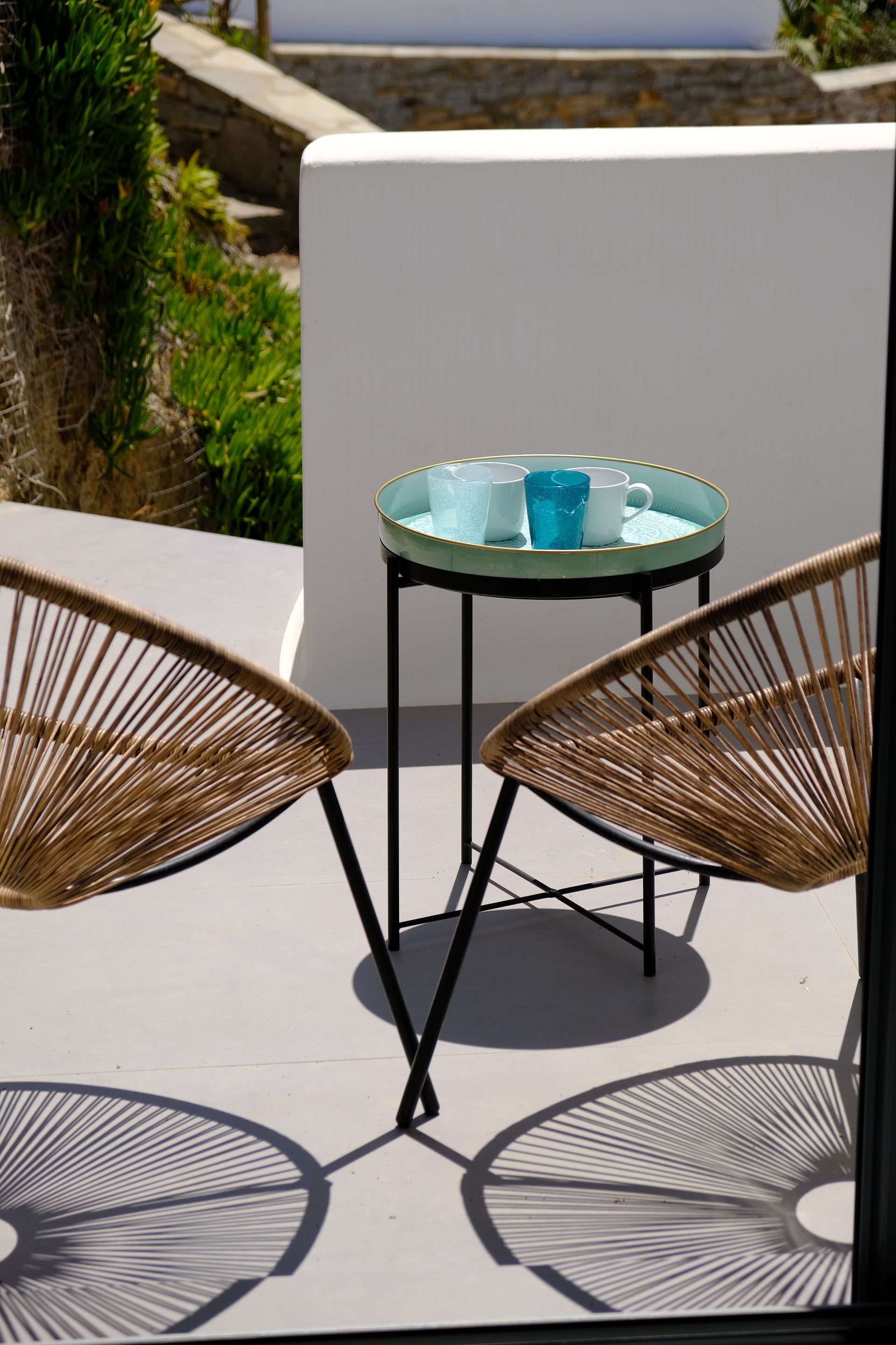 Two chairs are sitting next to a table with a cup on it.