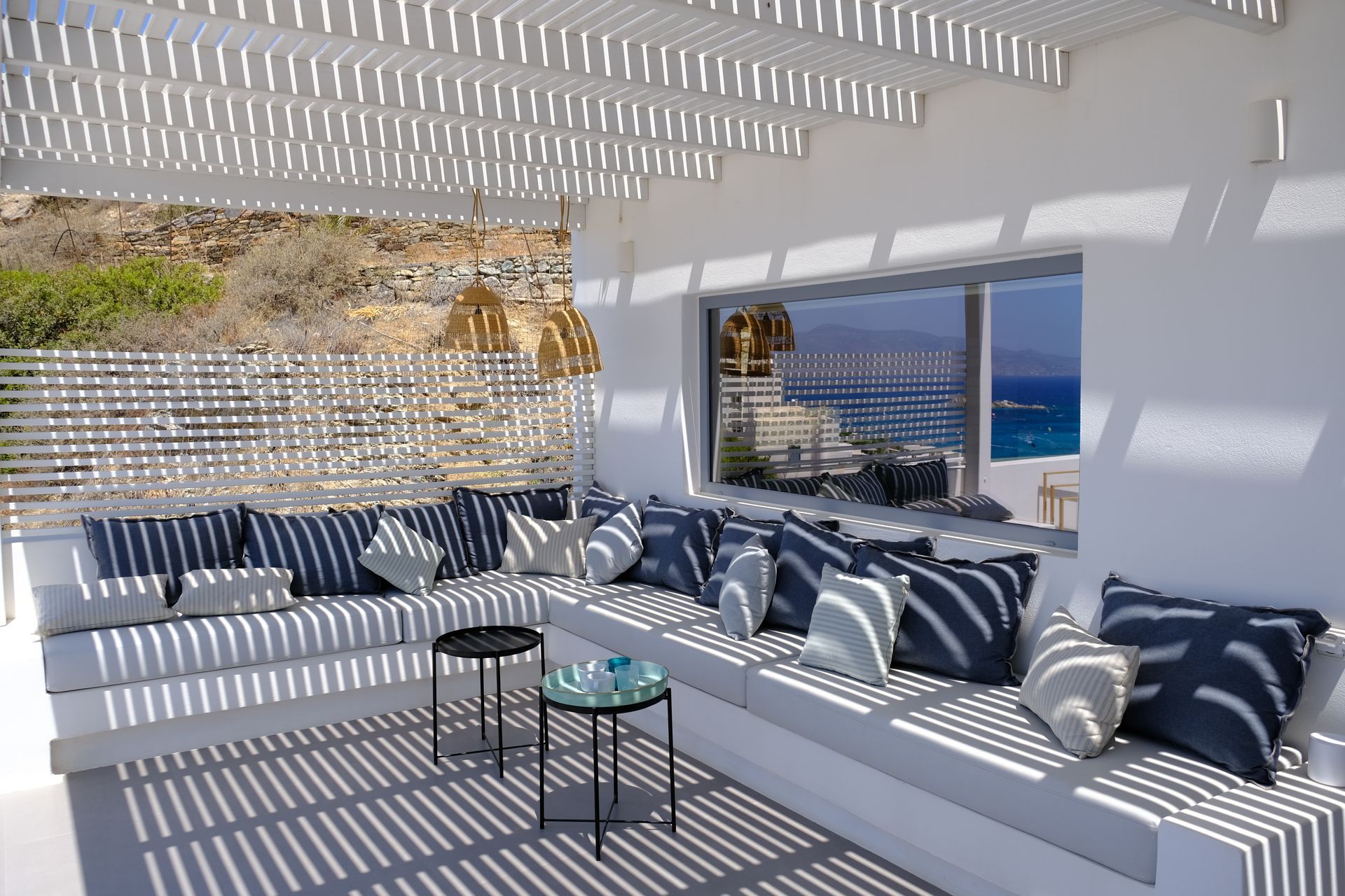 A patio with a couch and a window overlooking the ocean