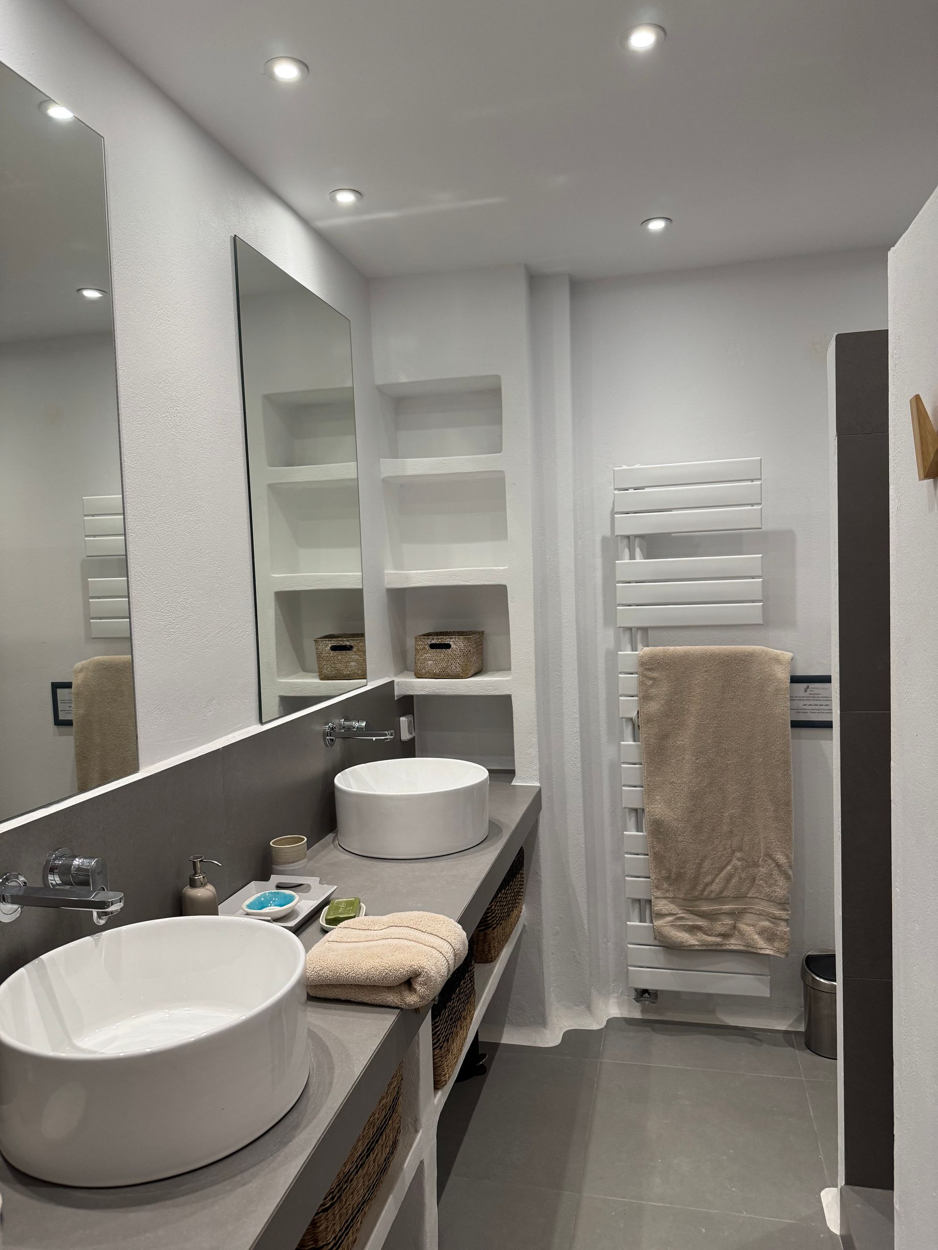A bathroom with two sinks , a mirror and a towel rack.