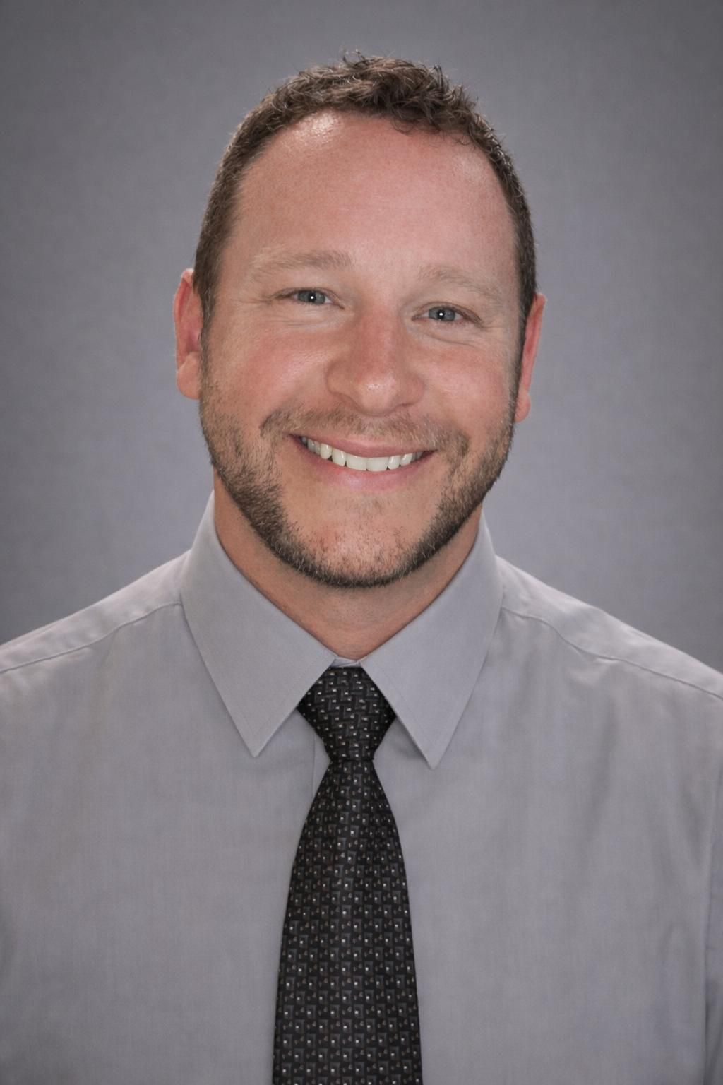 Three babies on a beach. Two in pink swimsuits, one in blue; one crying, two smiling. Beach setting with umbrella.