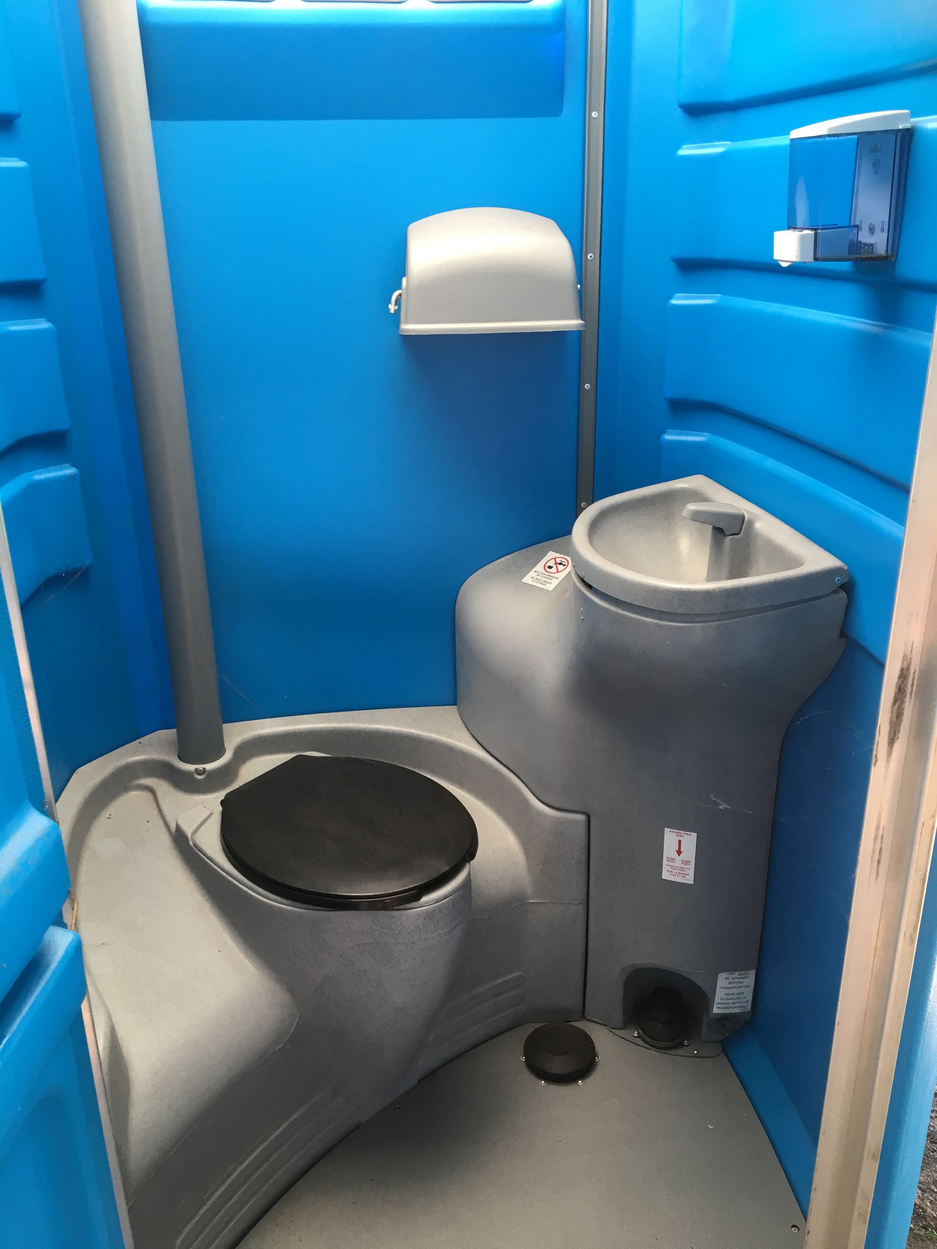 Interior of a blue portable toilet, featuring a toilet, sink, soap dispenser, and paper towel dispenser - Portable toilet hire for hire in Roseberry, NT