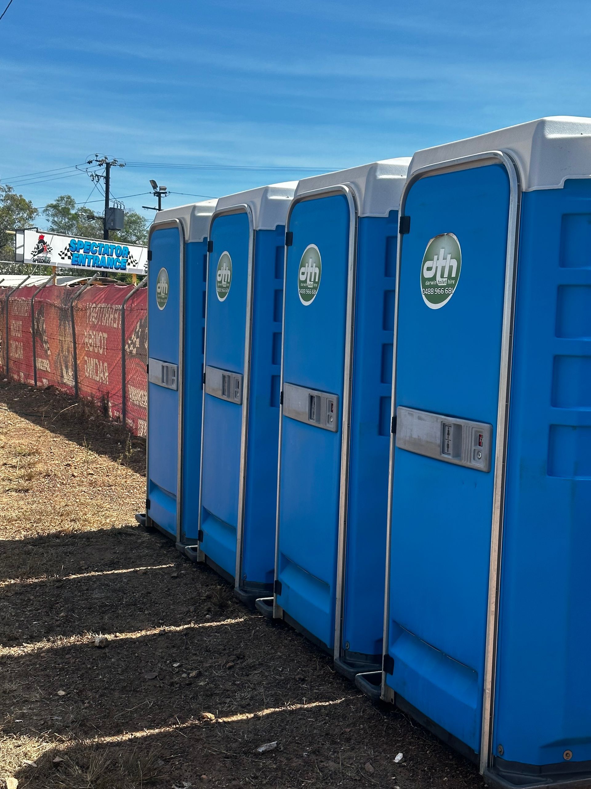Blue portable toilets lined up outdoors on gravel under a blue sky - Portable toilet hire for hire in Roseberry, NT