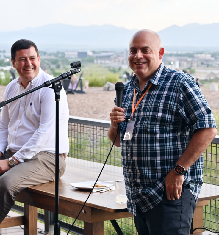 Two men are sitting at a table with a microphone in front of them