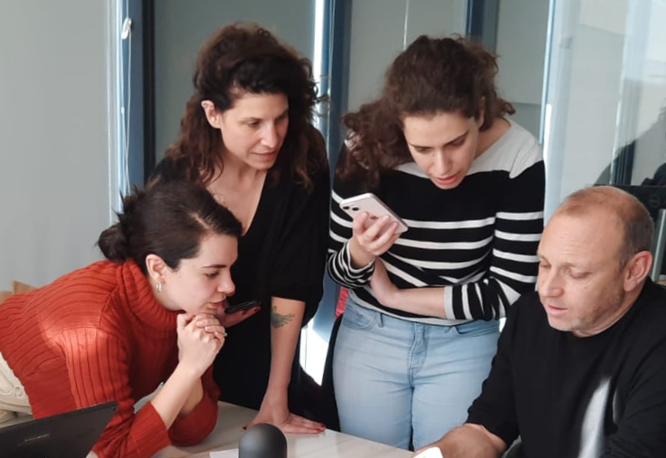 A group of people are looking at a cell phone.