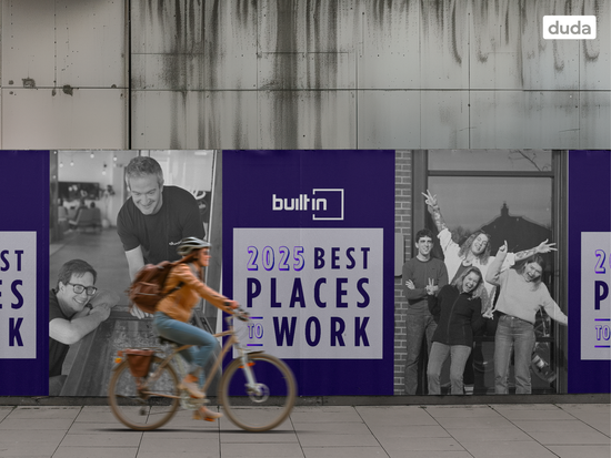 A woman is riding a bike in front of a wall that says 2025 best places to work.