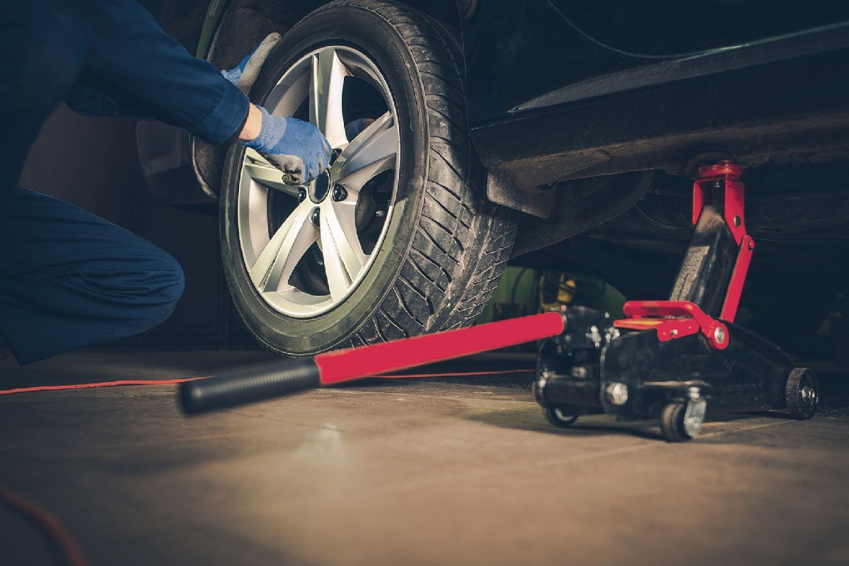 a man is changing a tire on a car in a garage .