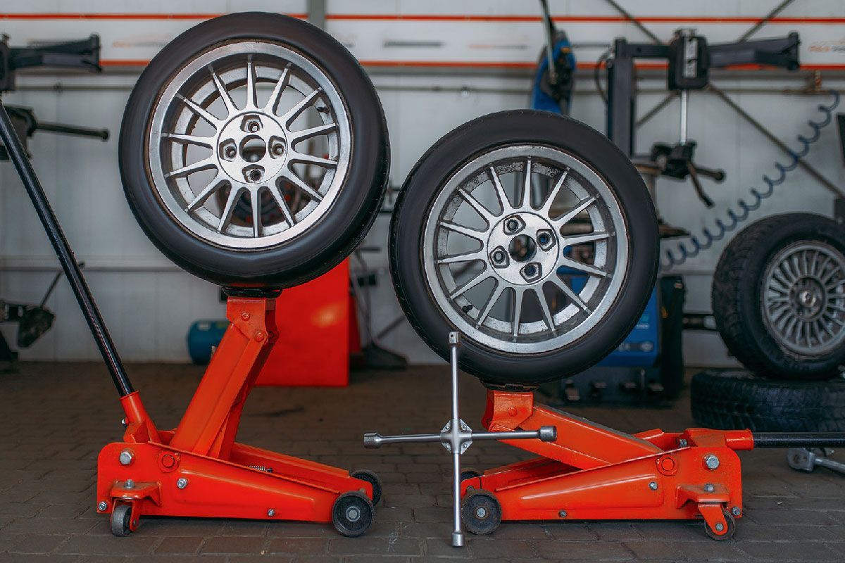 two tires are stacked on top of each other on a jack in a garage .