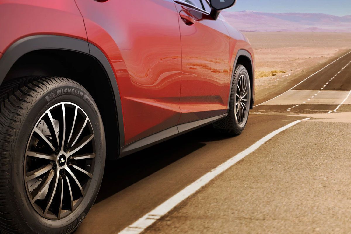 a red car is driving down a desert road