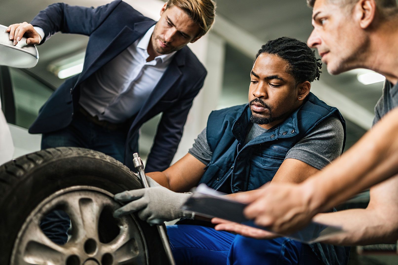 a group of men are working on a tire in a garage .