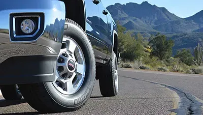 a truck is driving down a road with mountains in the background .