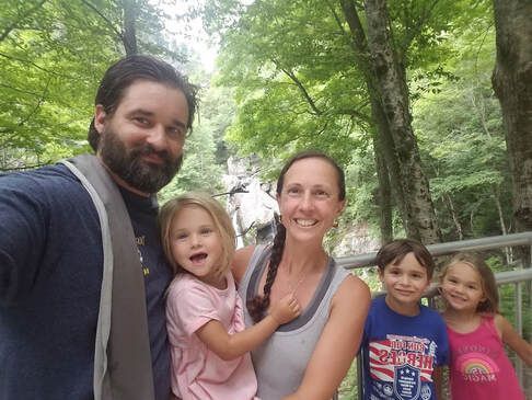 A family is posing for a picture in the woods.