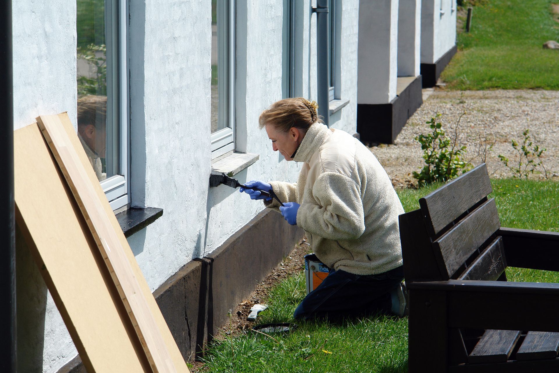 a woman paints the side of a building with a brush