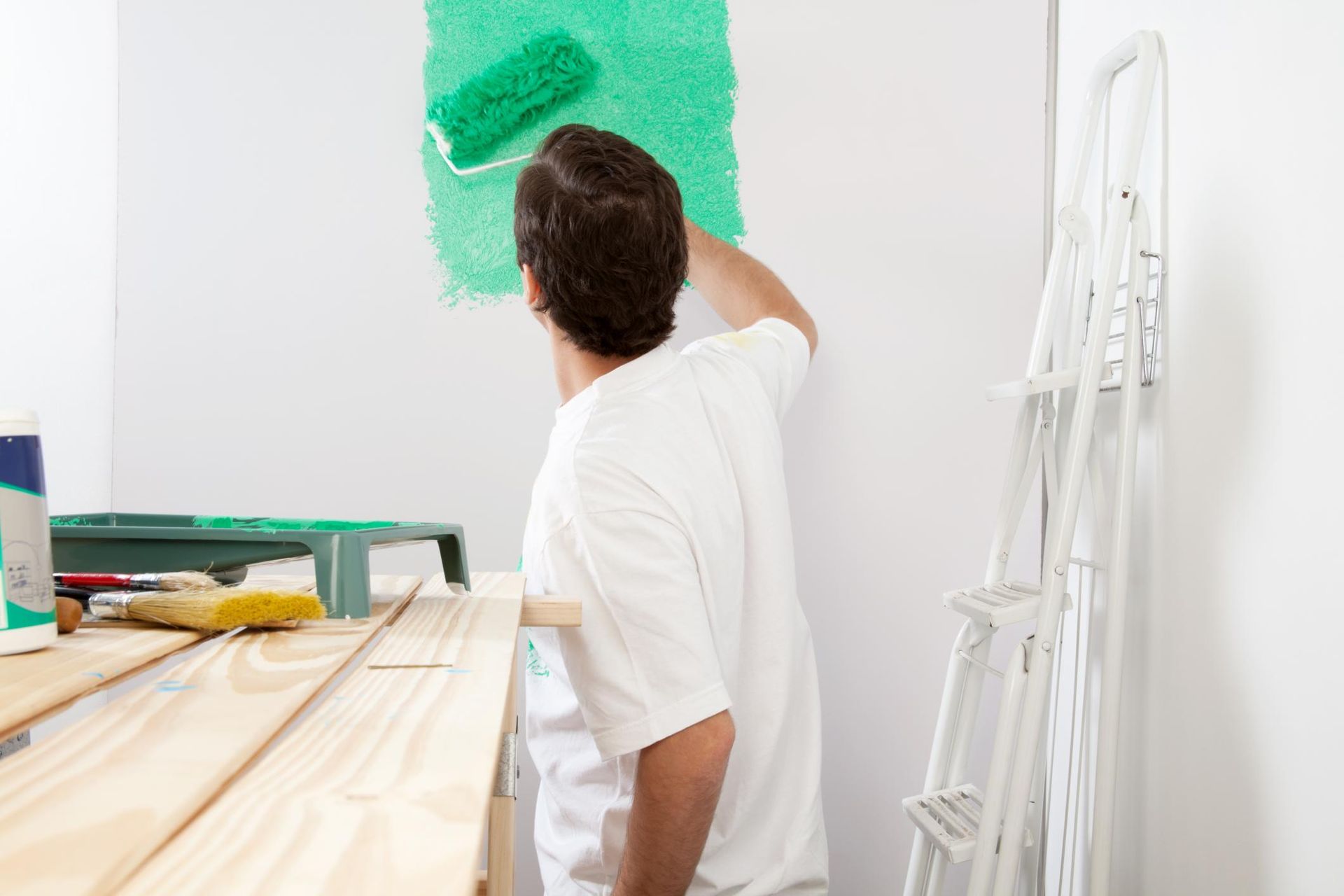 a man is painting a wall with green paint