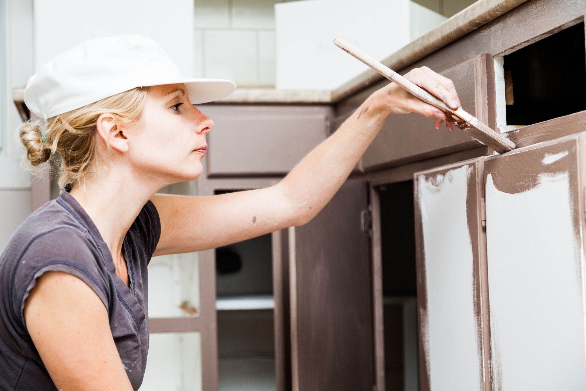 a woman is painting a cabinet with a brush
