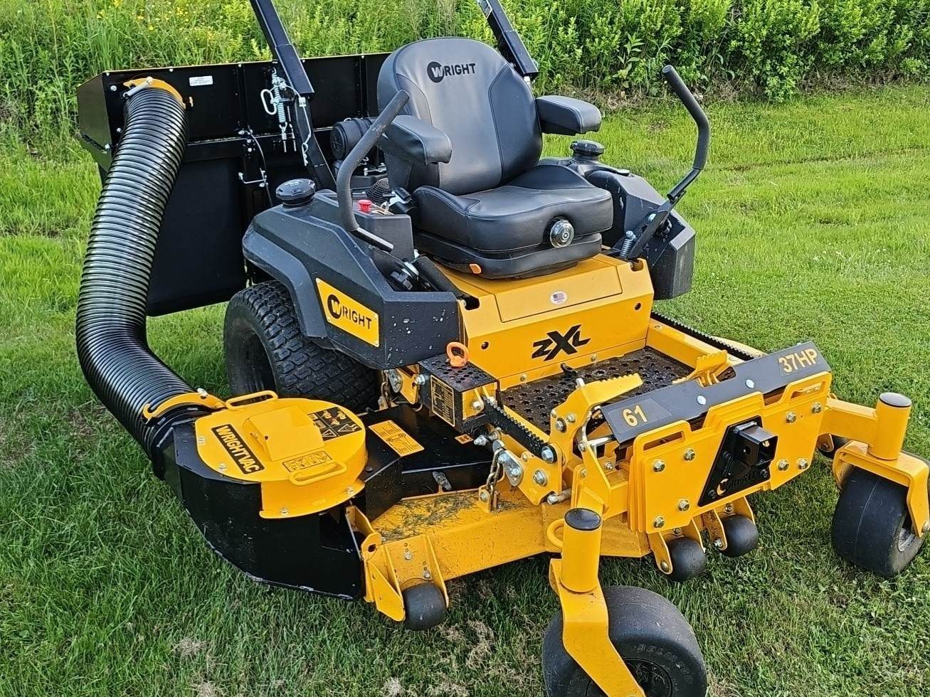 A yellow and black lawn mower is sitting on top of a lush green lawn.