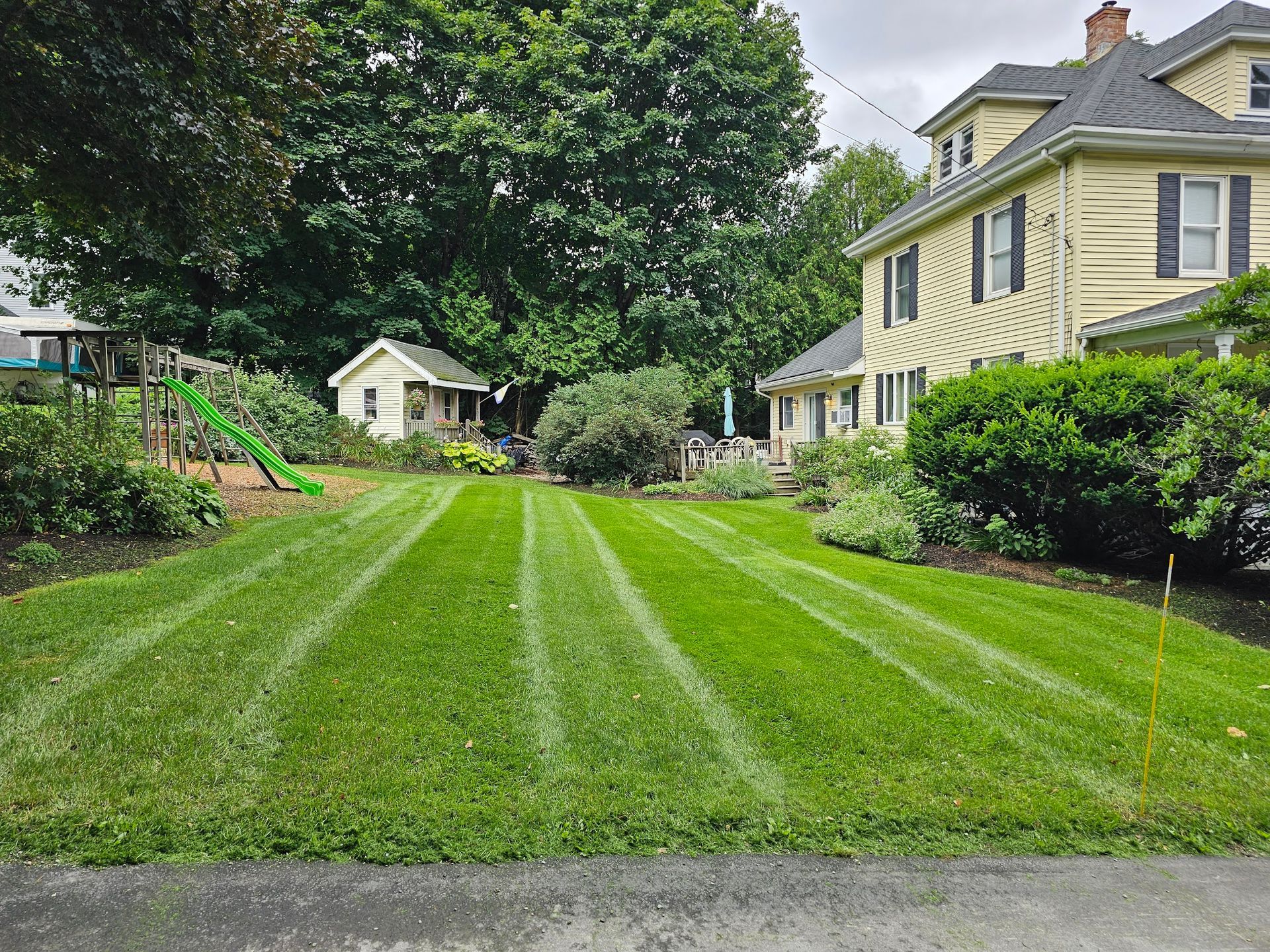 A lush green lawn is being mowed in front of a house.